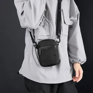 Men's black crossbody phone bag with USB port and adjustable branded woven strap