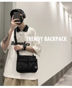 On-body view of black utility crossbody bag featuring dual front zipper pockets and strap