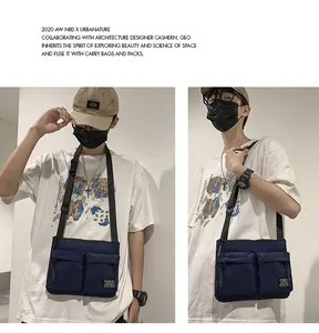 Detail view of navy blue canvas crossbody bag showing dual front utility pockets on model