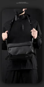 Black techwear messenger bag with waterproof coating and tactical buckle on male model