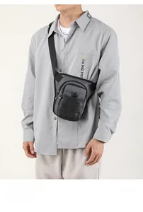 Détail du sac bandoulière tactique gris et noir avec plusieurs compartiments zippés