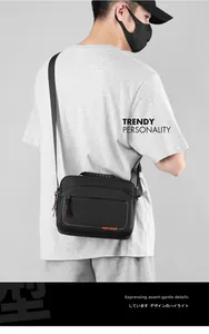 Close-up of the rubberized top handle and orange logo on this black crossbody bag