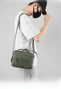 Detail of army green nylon messenger bag showing the brand logo and adjustable canvas strap