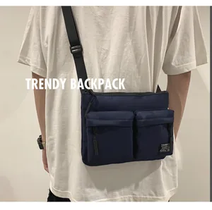 Side view of dark blue crossbody bag with double front flap pockets and wide nylon strap