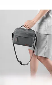 Close-up of a large capacity grey crossbody bag with orange logo and top handles
