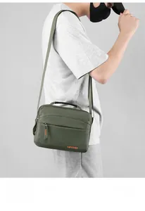 Detail view of large olive green crossbody bag with durable nylon and orange logo