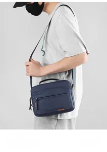Navy blue crossbody messenger bag with orange brand logo shown on model for casual wear