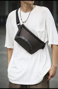 Gros plan d'un sac bandoulière marron avec logo porté sur un t-shirt blanc de style urbain