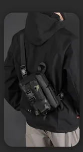 Sac bandoulière tactique en nylon noir et camouflage vert porté par un modèle homme