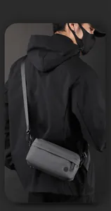 Male model wearing dark grey techwear nylon crossbody bag with adjustable strap