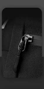 Detail shot of smooth black metal zipper and durable nylon fabric on men's crossbody bag