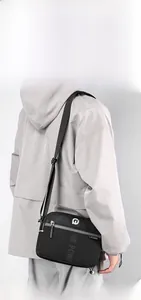 Détail d'une sacoche homme en nylon noir avec compartiments zippés et bandoulière réglable