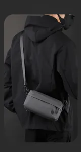 Detail of adjustable nylon strap and metal buckle on dark grey messenger bag