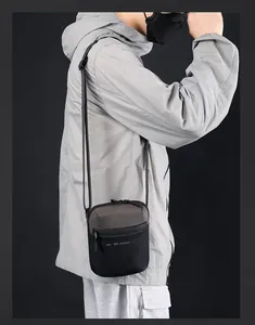Primer plano de un bolso bandolera compacto gris oscuro impermeable para hombre con estilo