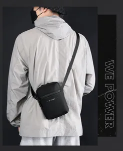 Bolso bandolera negro minimalista impermeable llevado por un modelo con correa ajustable