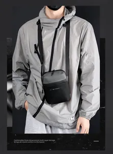 Detalle de la bandolera minimalista en negro y gris con correa de nailon ajustable para hombre