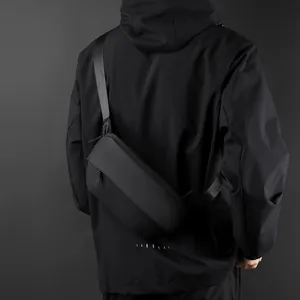 Minimalist black tactical sling bag for men with waterproof fabric on model's back