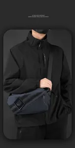 Detail van donkerblauwe crossbodytas met verstelbare riem en patch van het merklogo