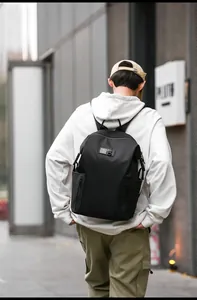 Outdoor shot of a black casual backpack with high-density texture and side zip pockets