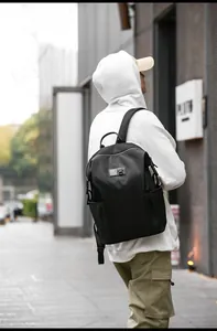 Outdoor shot of a black minimalist commuter backpack with adjustable padded straps on model