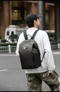 Close-up of a stylish black backpack for men with a square logo and side zipper details