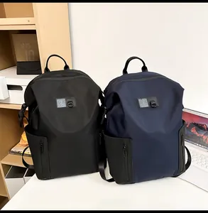 Close-up of waterproof nylon backpacks in black and navy on a desk with a laptop