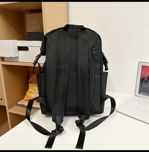 Detail of black casual backpack with padded straps and side pocket on a white desk