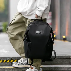 Minimalist black waterproof outdoor travel backpack for men shown in an urban street setting