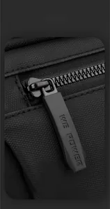 Close-up of durable textured nylon fabric and branded rubber zipper pull on black chest bag