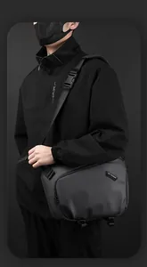 Détail du sac à bandoulière résistant à l'eau avec étiquette de marque en gris anthracite