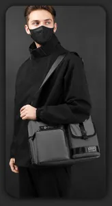 Detail of dark grey utility crossbody bag featuring buckle pocket and nylon strap