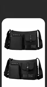Close-up of black nylon shoulder bag featuring multiple functional zipper pockets