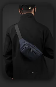 Close-up van een blauwe outdoor crossbodytas met meerdere ritsvakken en een brede schouderband