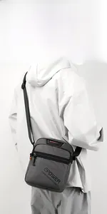 Detail of grey men's crossbody bag featuring wear-resistant fabric and orange accents