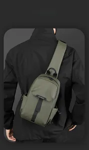 Rear view of an olive green waterproof nylon sling bag with adjustable strap on a model
