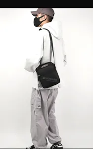 Close-up of black crossbody bag on model wearing white jacket and cargo pants