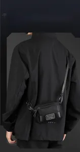 Detail of a black nylon crossbody bag featuring a metal brand plate and zipper layers
