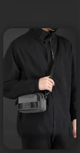 Detail of grey and black nylon crossbody bag with multi-layer zippers and adjustable strap