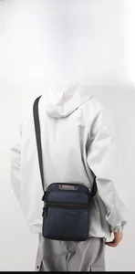 Detail of dark blue nylon crossbody bag featuring white logo and shoulder strap