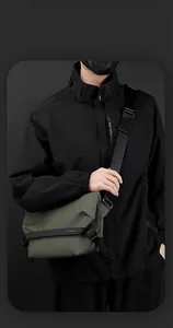Dettaglio di una borsa a tracolla verde oliva con cinturino nero e logo del marchio