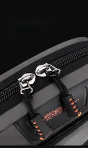 Close-up of durable dual zippers with orange pullers on a grey waterproof nylon bag