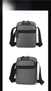 Detail of grey crossbody bag showing orange zipper pulls and black logo strap