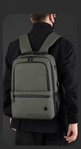 Detalle de mochila expandible verde oliva con puerto USB en un modelo masculino
