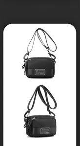 Detail view of the black nylon crossbody bag featuring multi-layer zippers and logo patch