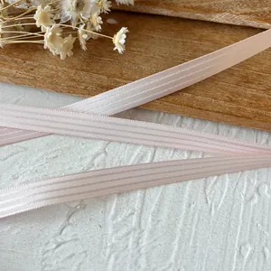 Close-up of light pink striped ribbon with translucent texture on a wooden background