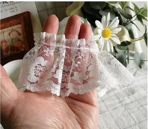 Dettaglio di pizzo bianco plissettato con motivo floreale per abiti di bambole