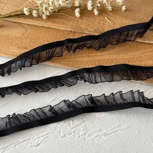 Detailed view of black elastic ruffled mesh lace trim for DIY sewing on a wood tray