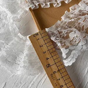 Pizzo plissettato bianco con ricamo floreale e righello che mostra la larghezza di 5 cm