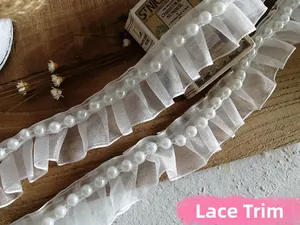 Detailed view of white pleated organza lace trim with elegant beaded pearl accents