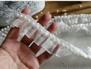 Detailed view of white pleated organza lace trim featuring elegant faux pearl bead accents